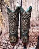Back view of the Mystic Pine Corral Boots with a wood backdrop.