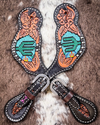 Beaded Cactus Ladies Spur Straps displayed on cowhide.