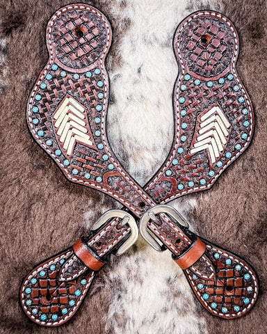 Turquoise Rawhide Ladies Spur Straps displayed on cowhide.
