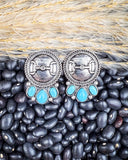 The Bitty Blue Stud Fashion Earrings displayed on play pebbled and wheat.