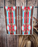 Ojo Caliente Towels displayed on a rod in front of wood background.