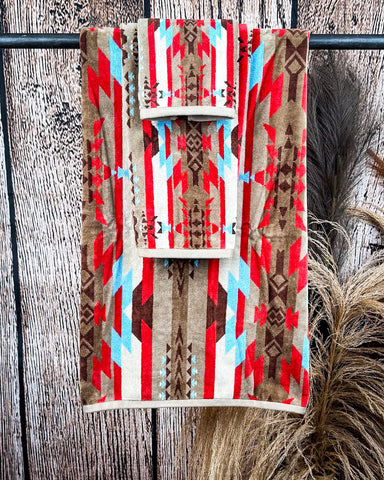 Ojo Caliente Towels displayed on a rod in front of wood background.