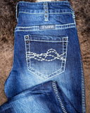 Close-up of blue jeans with 'Tuff' branding on a brown textured background