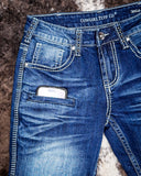 Close-up of blue jeans with 'Cowgirl Tuff Co.' branding on a textured surface.