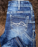 Stacked blue jeans on a brown surface
