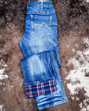 Folded blue jeans with plaid lining on a textured brown surface