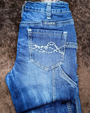 Folded blue jeans with 'TUFF' branding on a brown surface