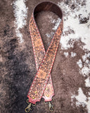 Decorative leather purse strap with floral patterns on a textured surface