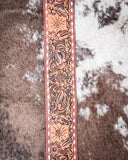 Decorative leather purse strap with floral patterns on a textured surface