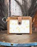 The Wind Rider Card Holder in Brown, on a wooden table with a wood backdrop and wheat in the back.