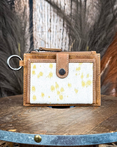 The Wind Rider Card Holder in Brown, on a wooden table with a wood backdrop and wheat in the back.