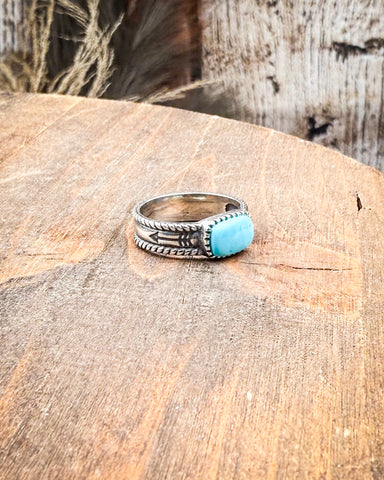 Silver ring with a turquoise stone on a wooden surface