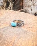 Silver ring with turquoise stone on a wooden surface