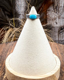 Turquoise ring on a cone-shaped display with wooden base and rustic background
