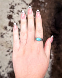 Hand wearing a turquoise ring with a blurred background