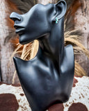 Black bust with a turquoise earring on a rustic wooden background