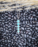 Necklace with a turquoise pendant on black beans