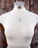 Mannequin torso wearing a turquoise necklace with a wooden background