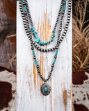 Layered necklace with faux turquoise beads on a wooden surface