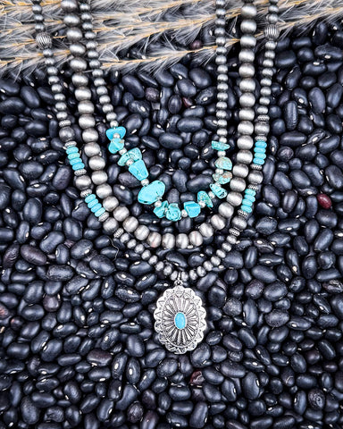 Necklace with faux turquoise stones and silver pendant on black beans