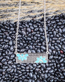 Necklace with a bar pendant on a bed of black beans