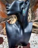 Earrings on a black mannequin bust with a rustic background