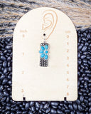 Earring on a measurement card with black beans in the background