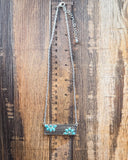 Necklace with faux turquoise stones on a wooden surface with a ruler for scale.