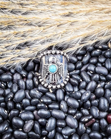Silver ring with faux turquoise stone on black beans and wheat background