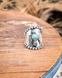 Silver ring with a faux turquoise stone on a wooden surface