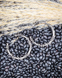 Black beans and wheat with barbed wire hoops on a textured surface