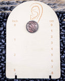 Jewelry measurement card with a copper and silver earring on a white background