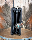 Black leather wallet with decorative buckle on a wooden surface