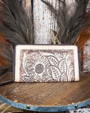 Leather wallet with floral embossing on a wooden surface