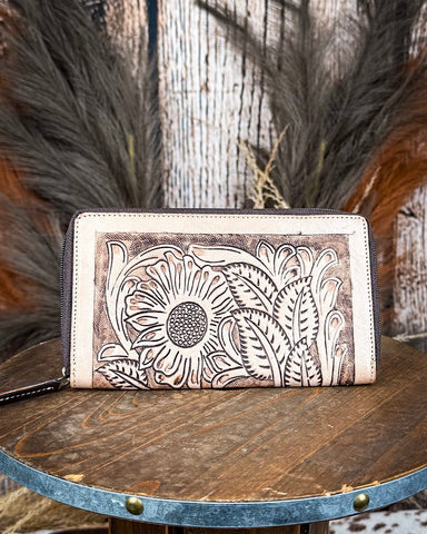 Leather wallet with floral embossing on a wooden surface