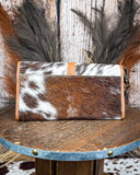 Brown and white cowhide wallet on a wooden surface with a rustic background