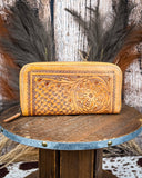 Handcrafted leather wallet with intricate patterns on a wooden stand.
