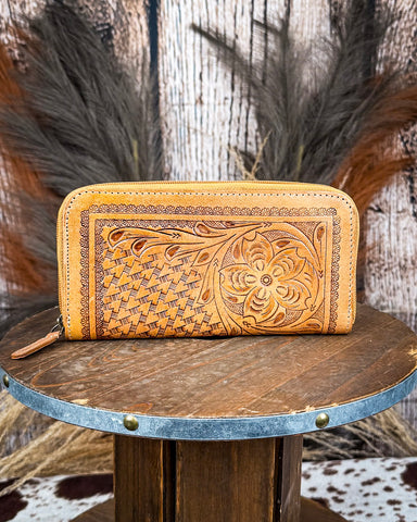 Handcrafted leather wallet with intricate patterns on a wooden stand.
