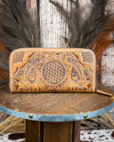 Tooled leather wallet on a wooden stand with a rustic background