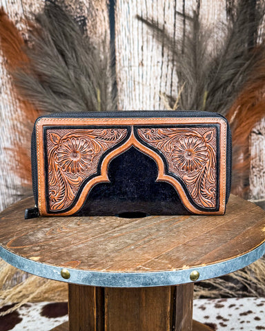 Handcrafted leather wallet with intricate designs on a wooden surface.