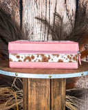 Pink jewelry box with cow print on a wooden surface