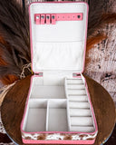 Pink jewelry case with compartments on a wooden surface