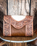 Handcrafted leather bag with intricate designs on a wooden surface