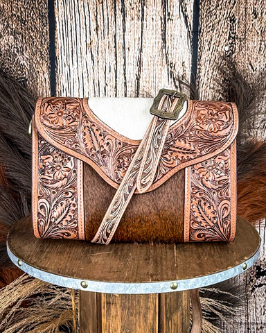 Brown leather handbag with intricate patterns on a wooden surface