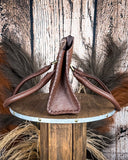 Brown leather bag on a wooden stand with a rustic background