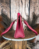 Red leather handbag on a wooden stand with a rustic background