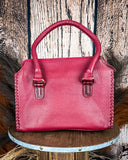 Red leather handbag on a wooden stool with a rustic background