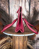 Red leather bag on a wooden stand with a rustic background