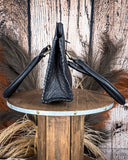 Black leather bag on a wooden stand with a rustic background