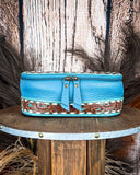 Blue leather make up bag with intricate designs on a wooden surface